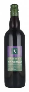 A dark bottle, with a great cap and a green label, the top of which is purple. The label reads "St Anne's Old Oak Tawny".